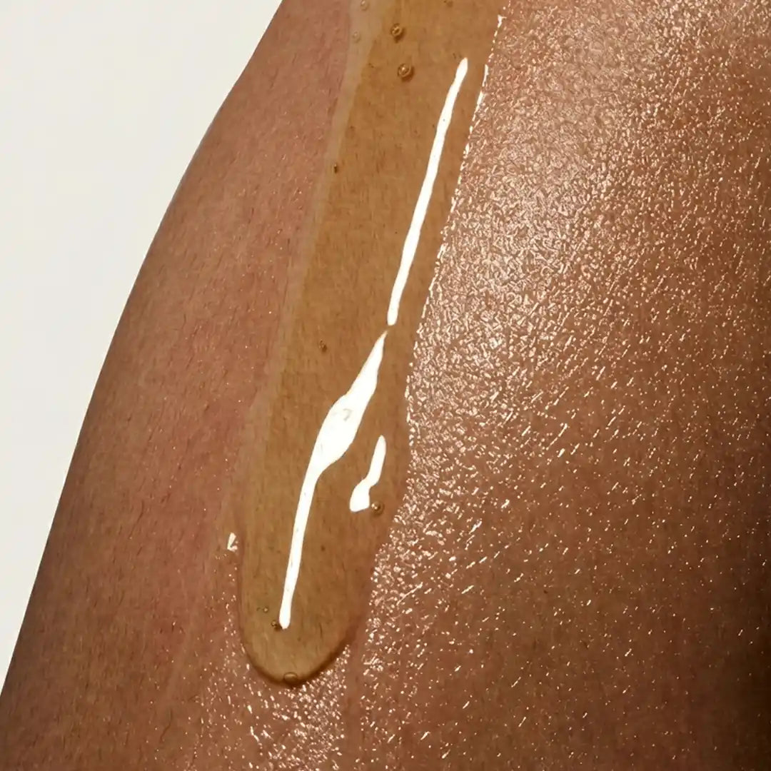 Close-up of lightweight body serum dripping on Indian skin. 